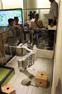 Visitors operate a prototype of a robot arm.