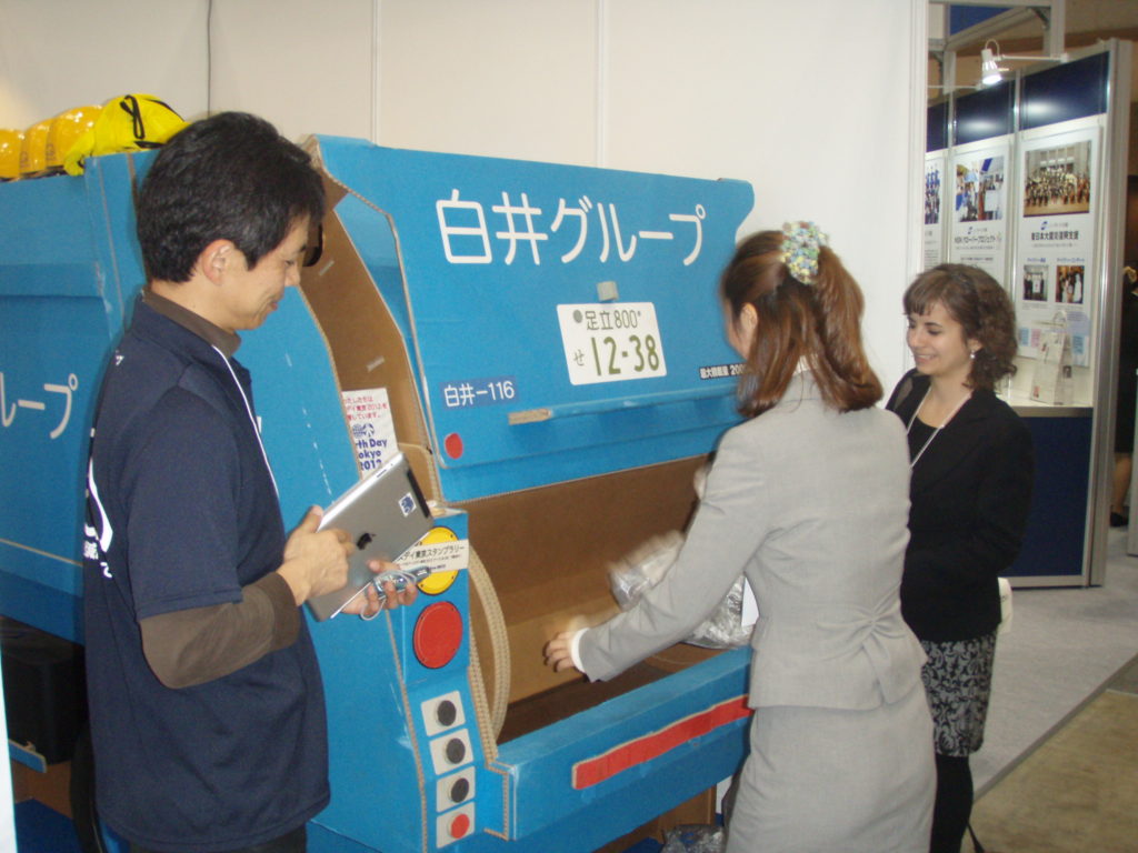 Demonstrating the garbage collector vehicle at the exhibition in Tokyo with foreign internship students