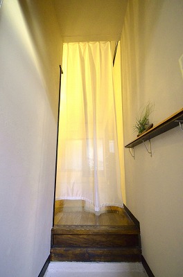 A long white mesh curtain and a narrow shelf to the wall in the entryway